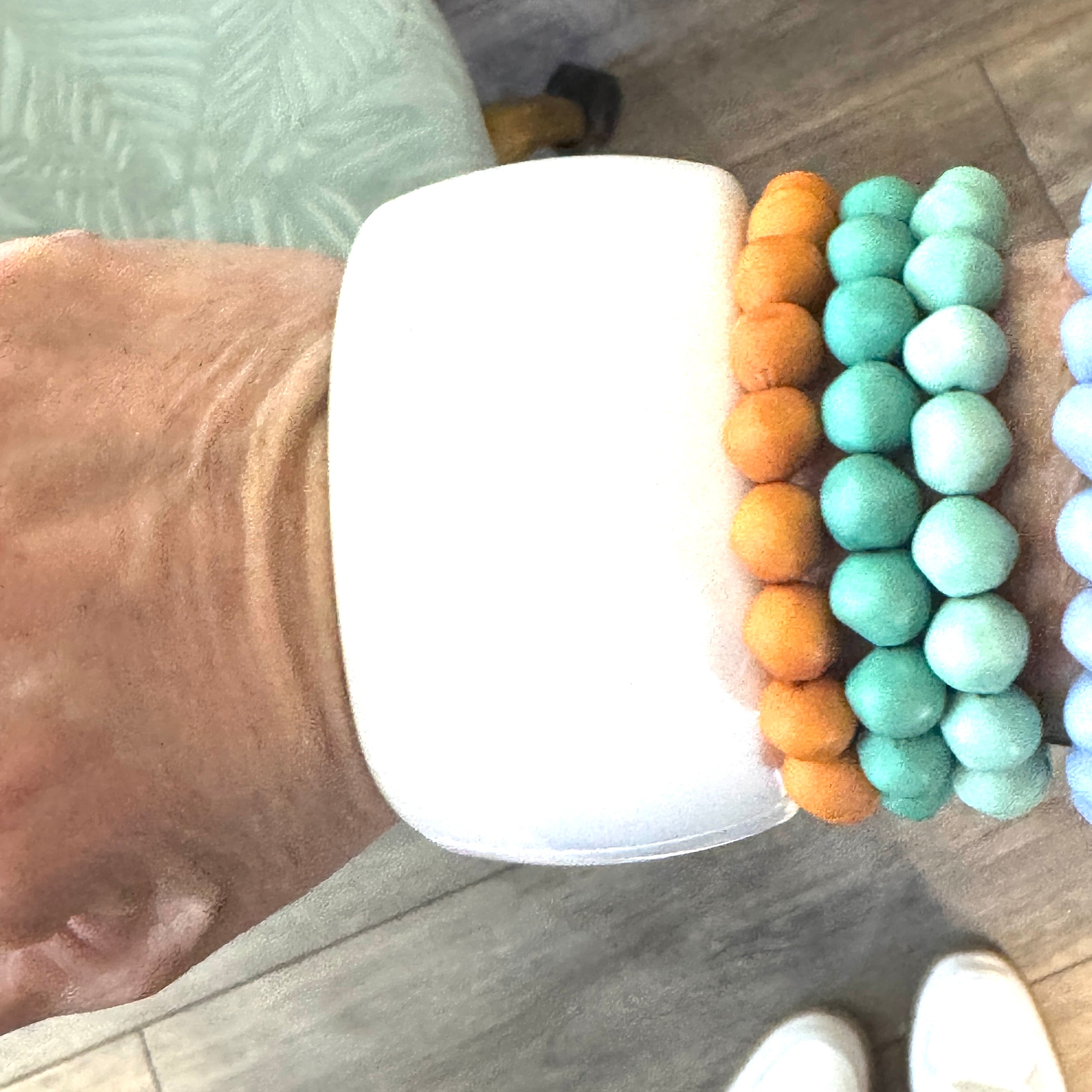 white lucite clamper cuff bracelet worn on the wrist alongside beaded bracelets