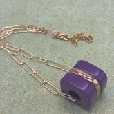 Chain necklace with a purple pendant on a textured surface