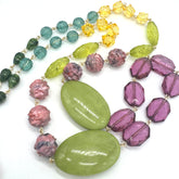 Colorful beaded necklace with green, purple, and yellow beads on a white background