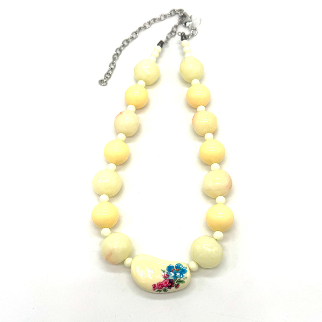 Necklace with cream-colored beads and a floral focal on a white background