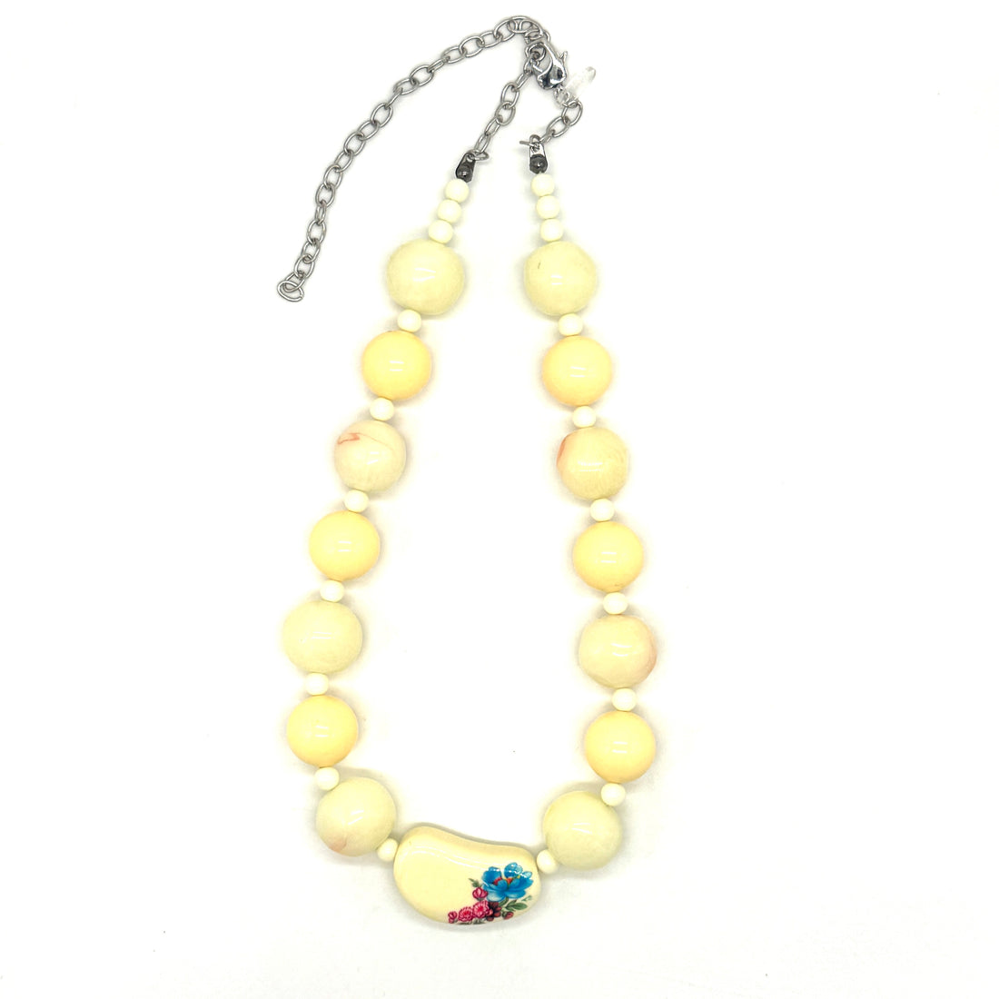 Necklace with yellow beads and a floral focal bead on a white background