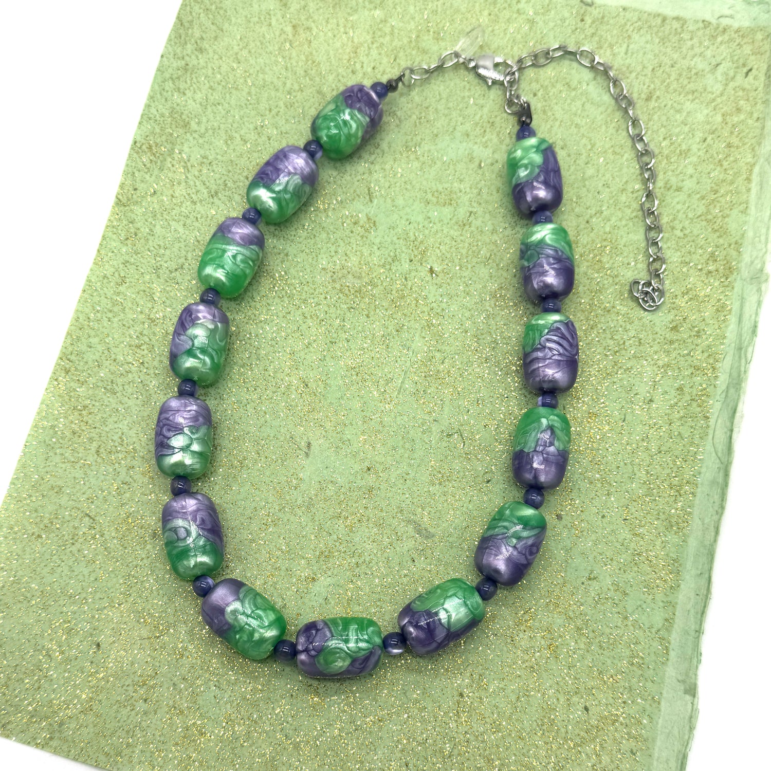 Necklace with green and purple beads on a green background