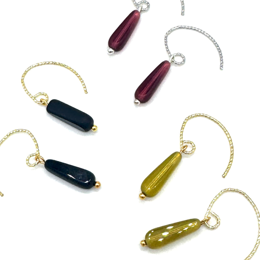 Earrings with teardrop-shaped beads on gold and silver earwires against a white background