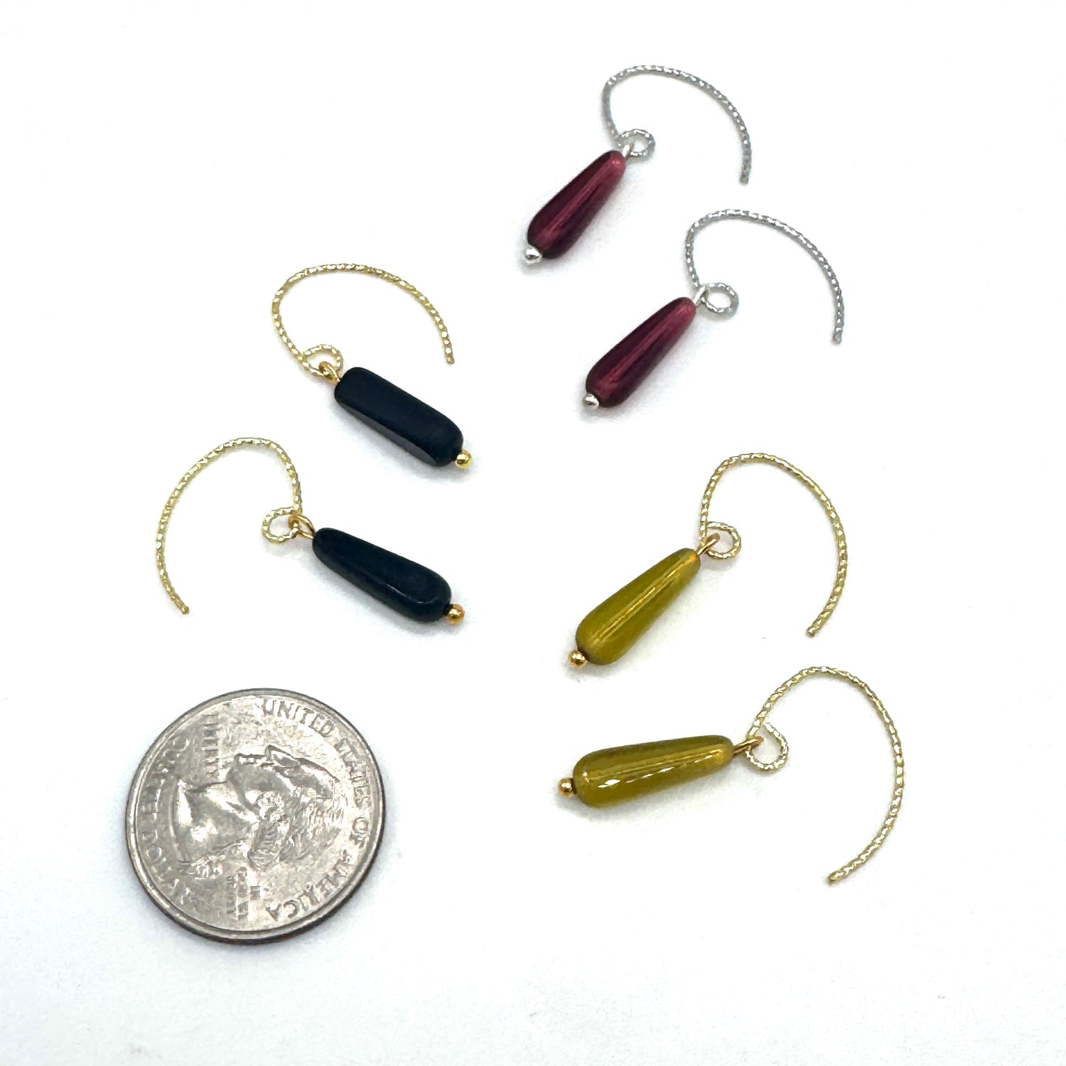Set of three earrings with different colored beads on a white background, one quarter coin for scale.