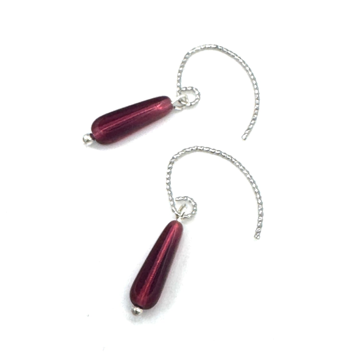 Pair of red teardrop-shaped earrings with silver chains on a white background