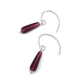 Pair of red teardrop-shaped earrings with silver chains on a white background