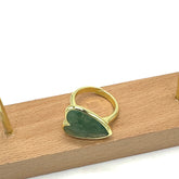 Gold ring with a green stone on a wooden stand