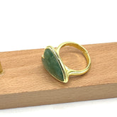 Gold ring with a green stone on a wooden surface