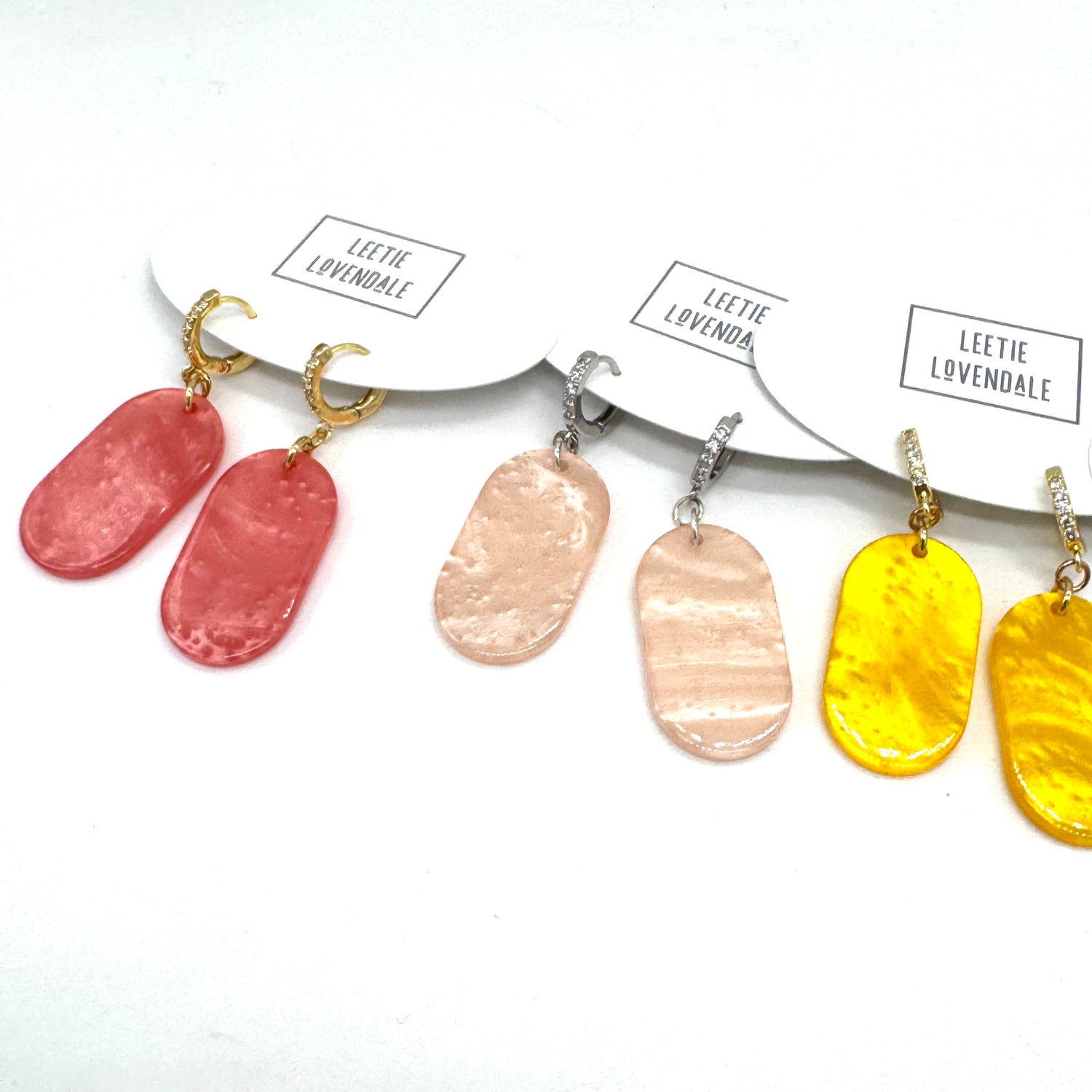Set of earrings with different colored pendants on a white background, branded &