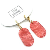 Pink earrings with gold earwires on a white background, featuring the brand &