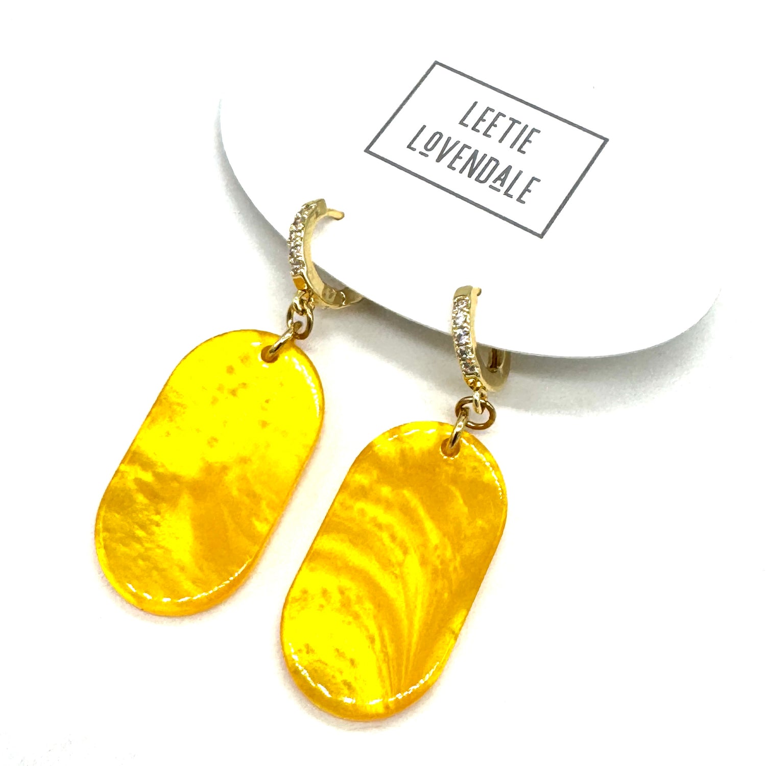 Yellow marbled earrings on a white background with &