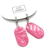 Pink earrings on a white background with &