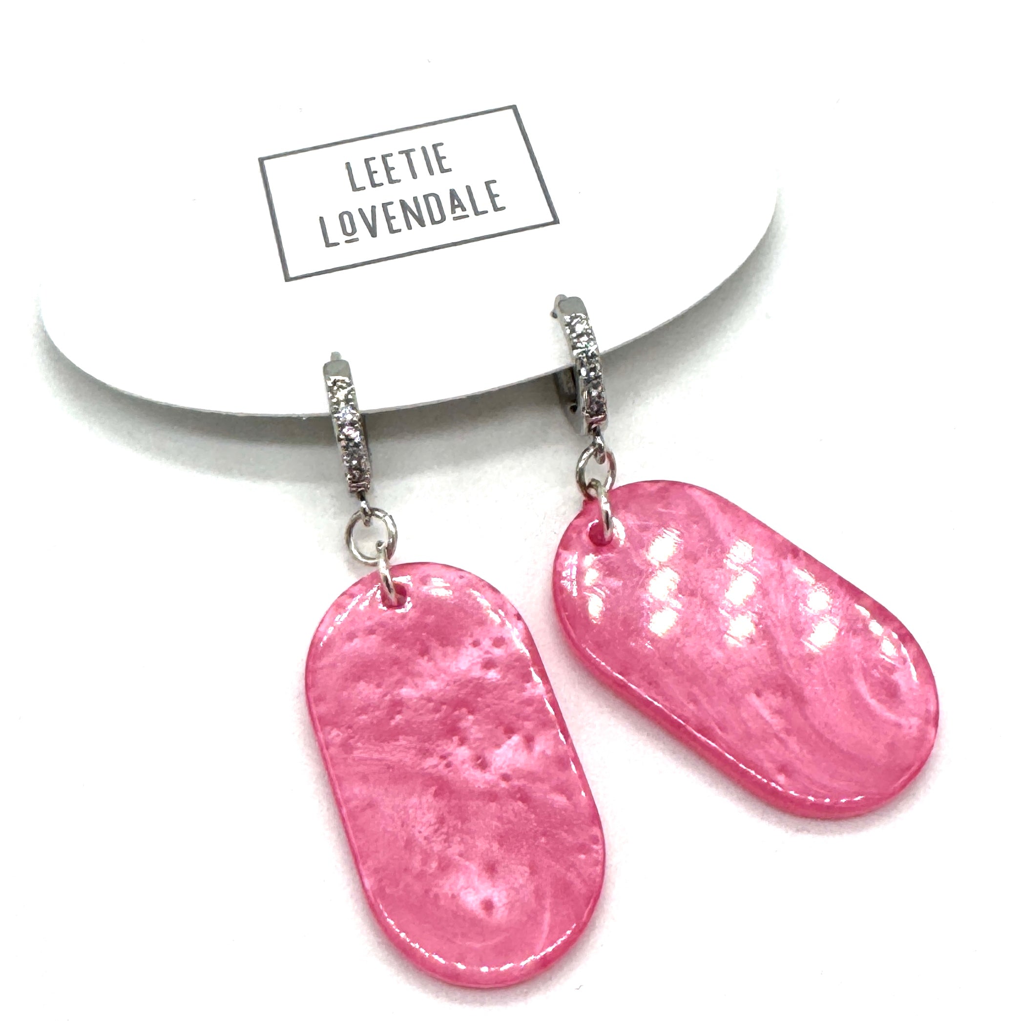 Pink earrings on a white background with &