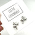 Silver frog-shaped earrings on a card with &