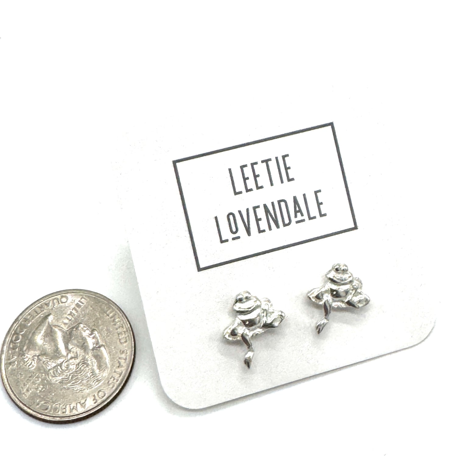 Silver frog-shaped earrings on a card with &