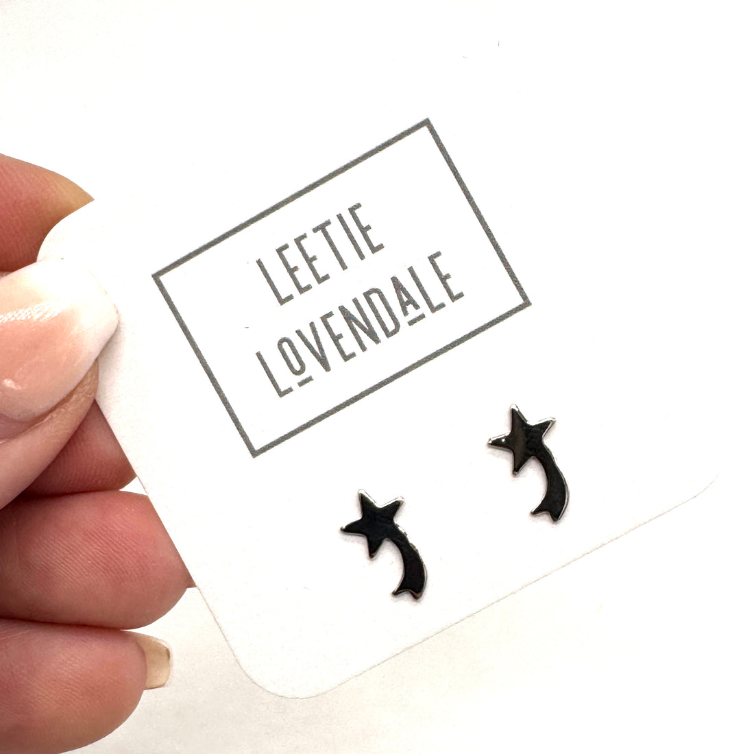 Black shooting star earrings on a white card with &