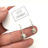 Silver turtle earrings held between fingers with &