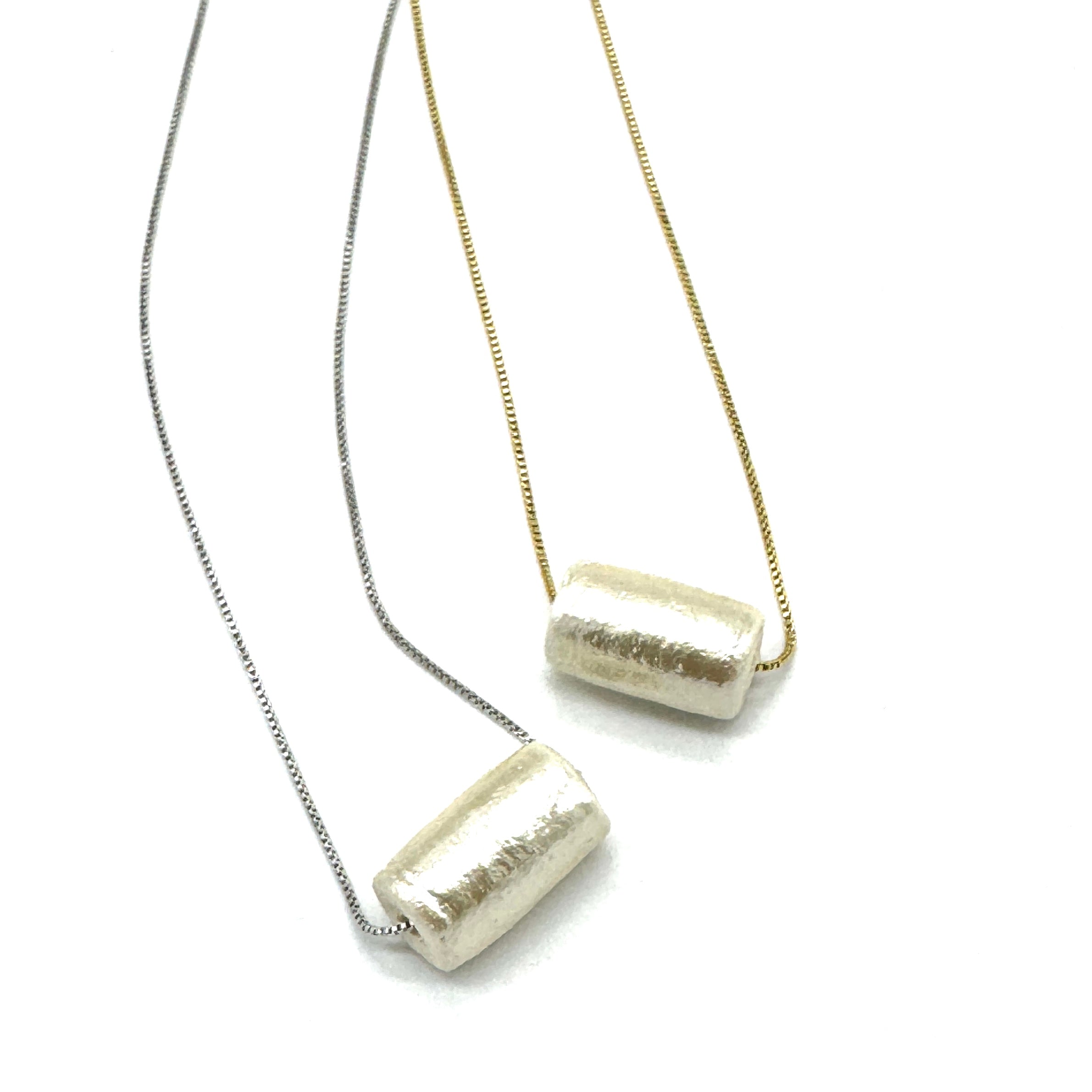 Two necklaces with cylindrical pendants on a white background