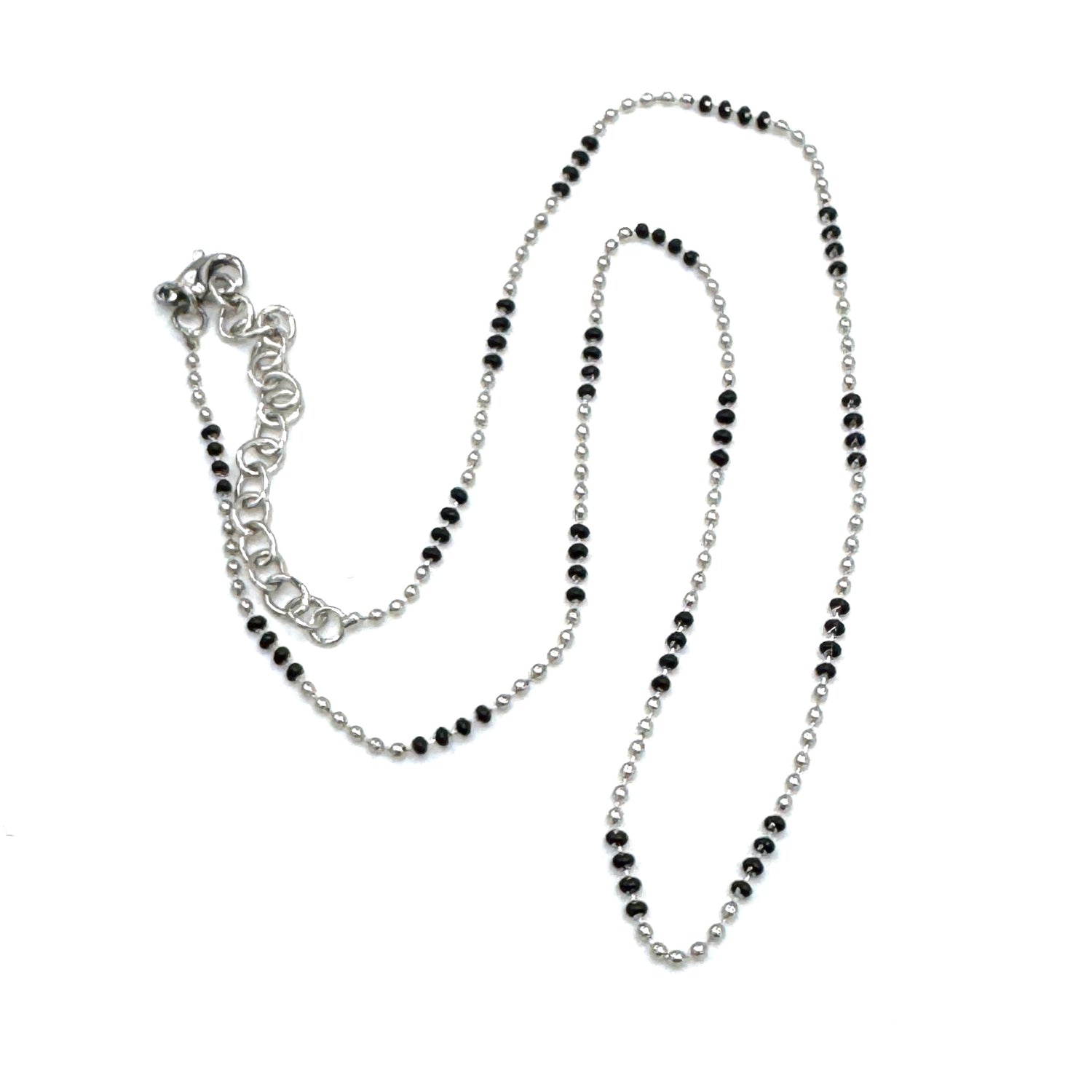 Silver necklace with black beads on a white background