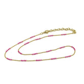 Gold and pink beaded necklace on a white background