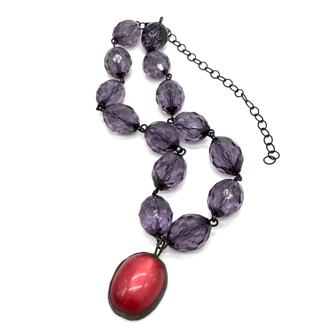 Necklace with purple beads and a red pendant on a white background