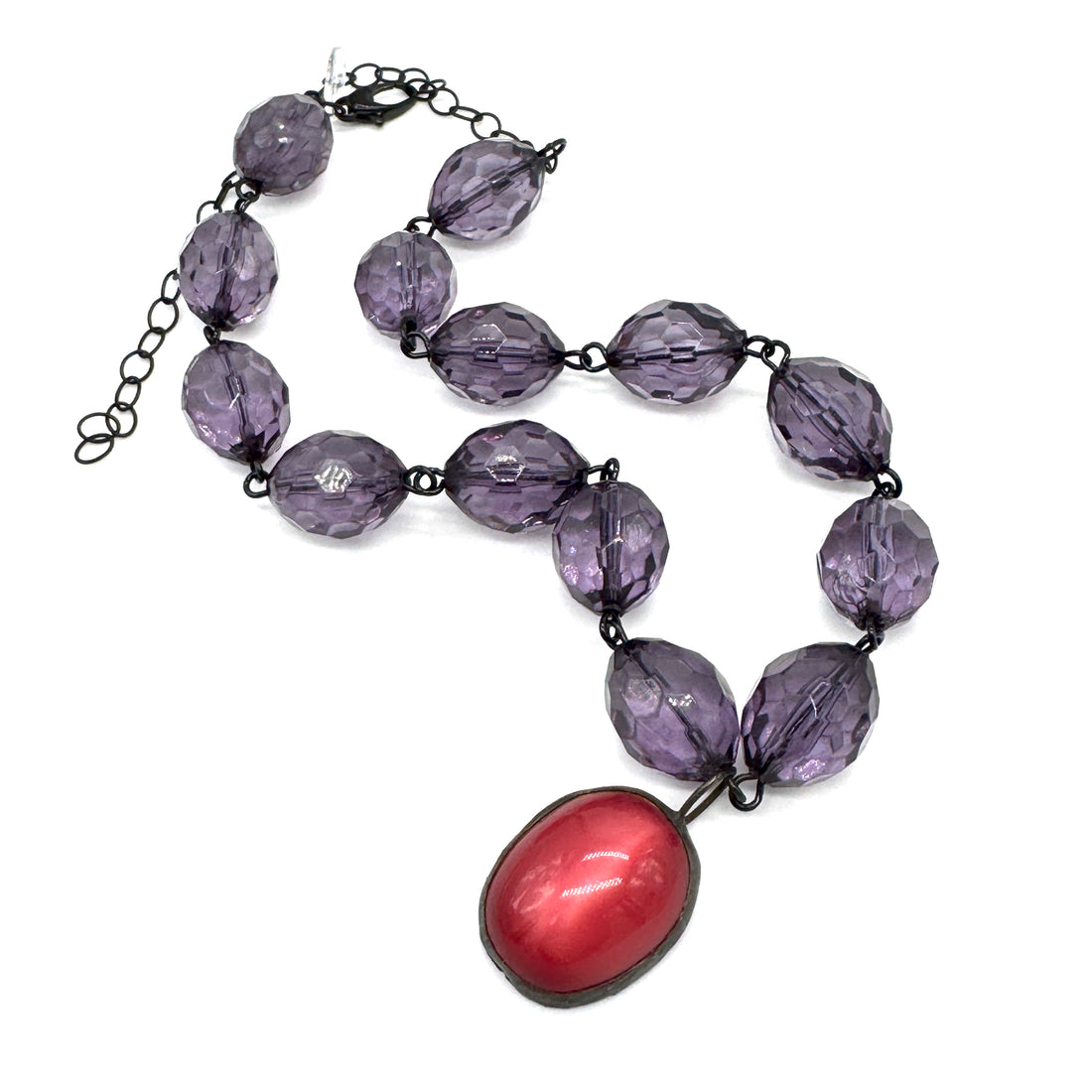 Necklace with purple beads and a red pendant on a white background