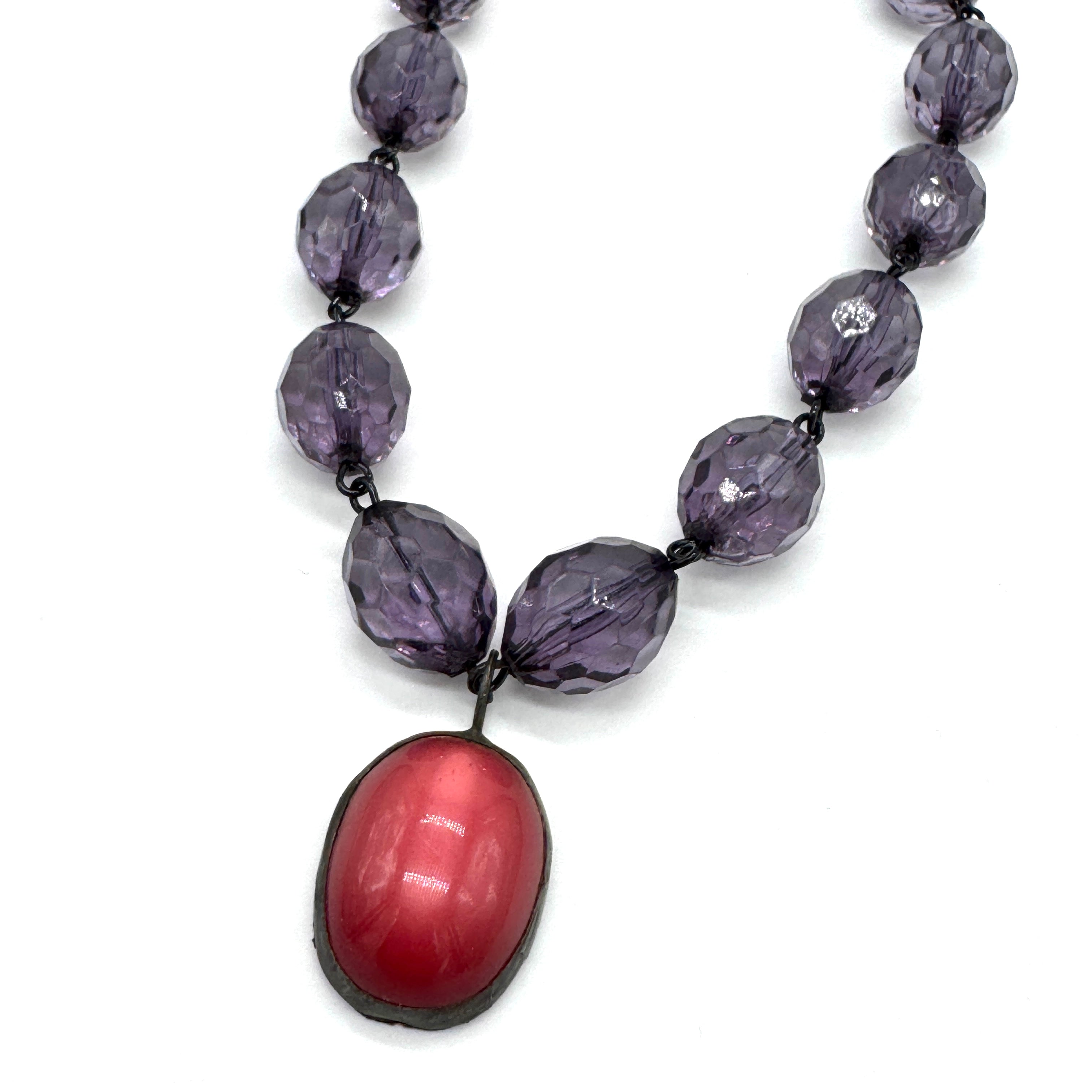 Necklace with purple beads and a pink pendant on a white background
