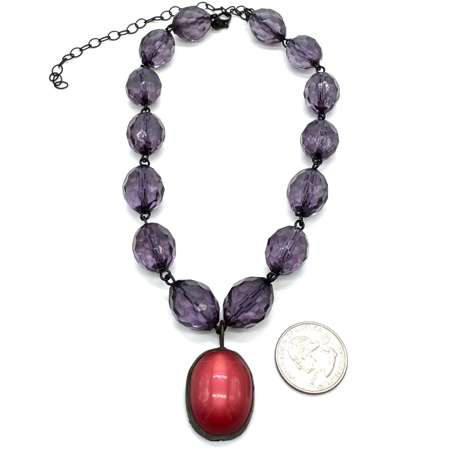 Necklace with purple beads and a red pendant on a white background