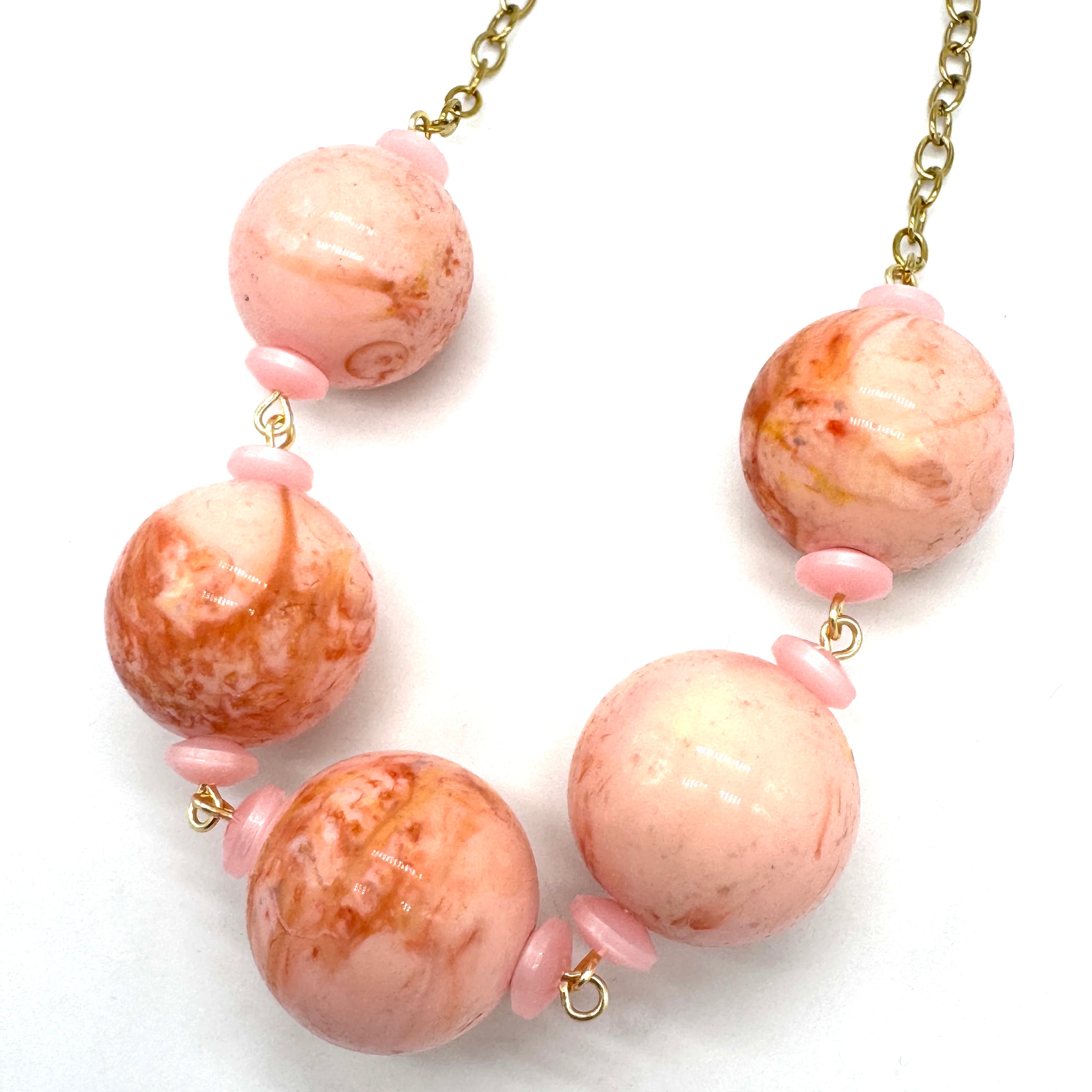 Necklace with pink and gold beads on a white background