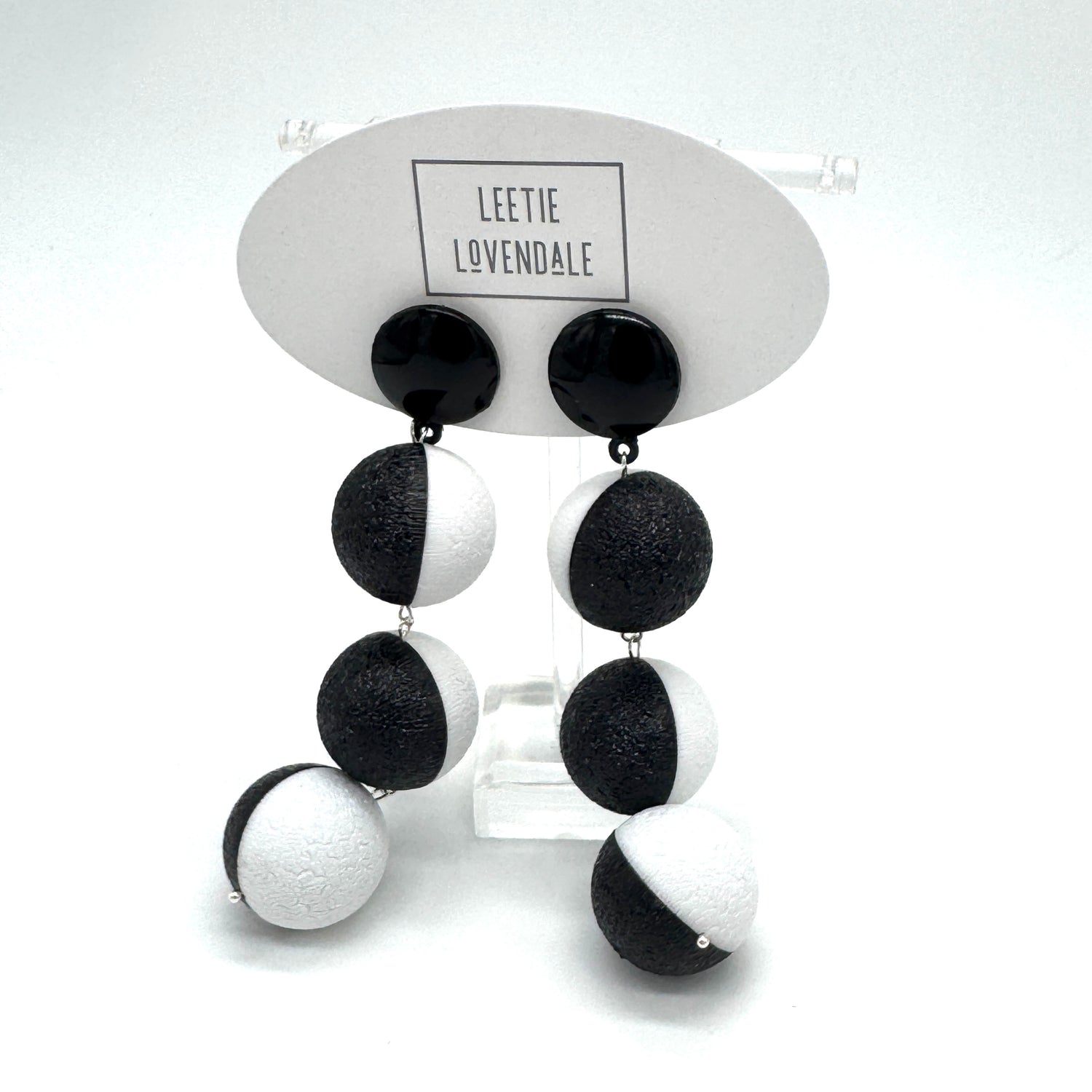 Black and white earrings on a display card with &