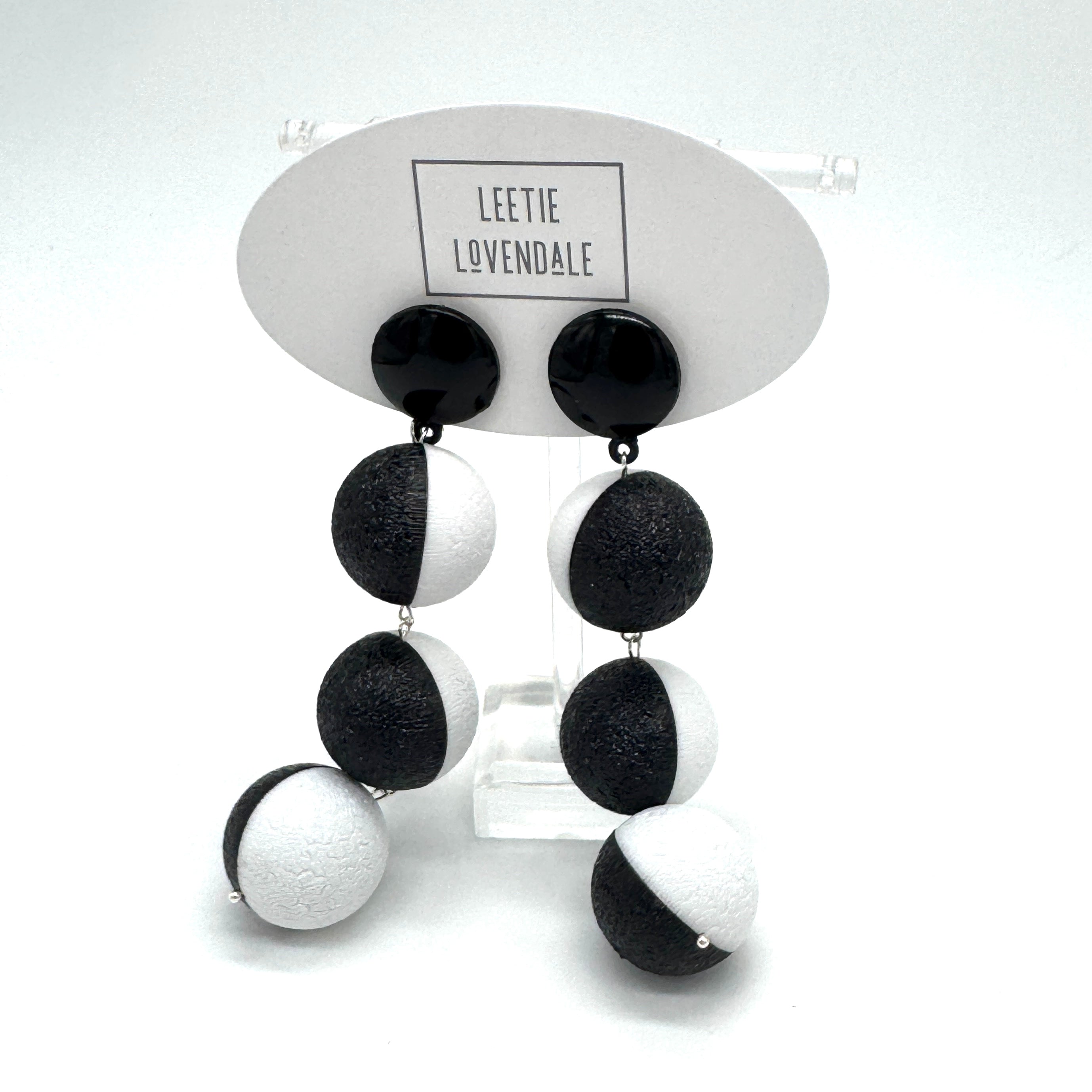 Black and white earrings on a display card with &