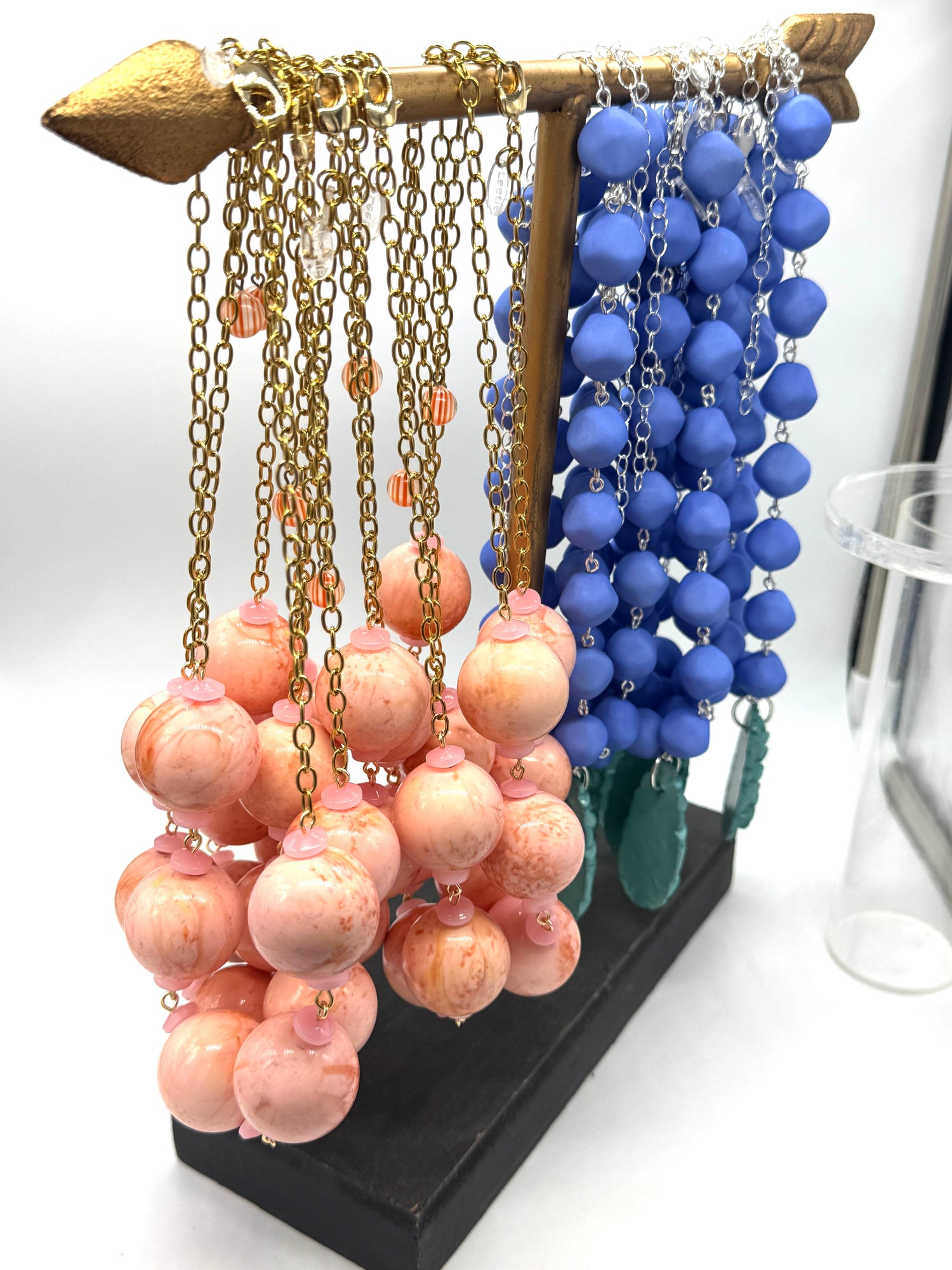 Necklace stand with pink and blue beaded necklaces on a white background