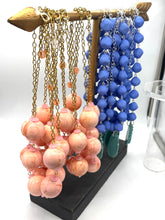 Necklace stand with pink and blue beaded necklaces on a white background