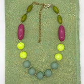 Necklace with green, yellow, and pink beads on a green background