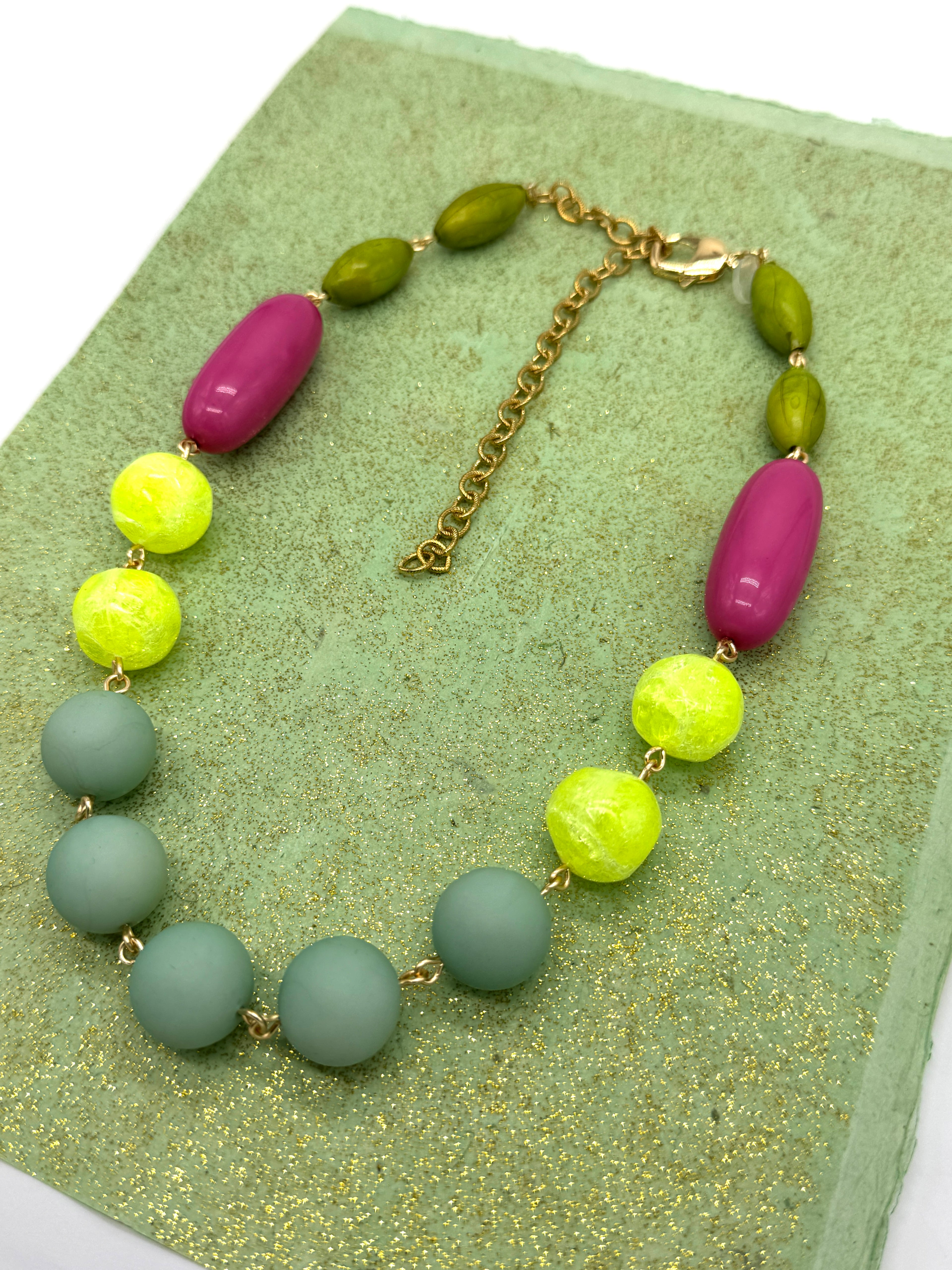 Necklace with colorful beads on a green textured surface