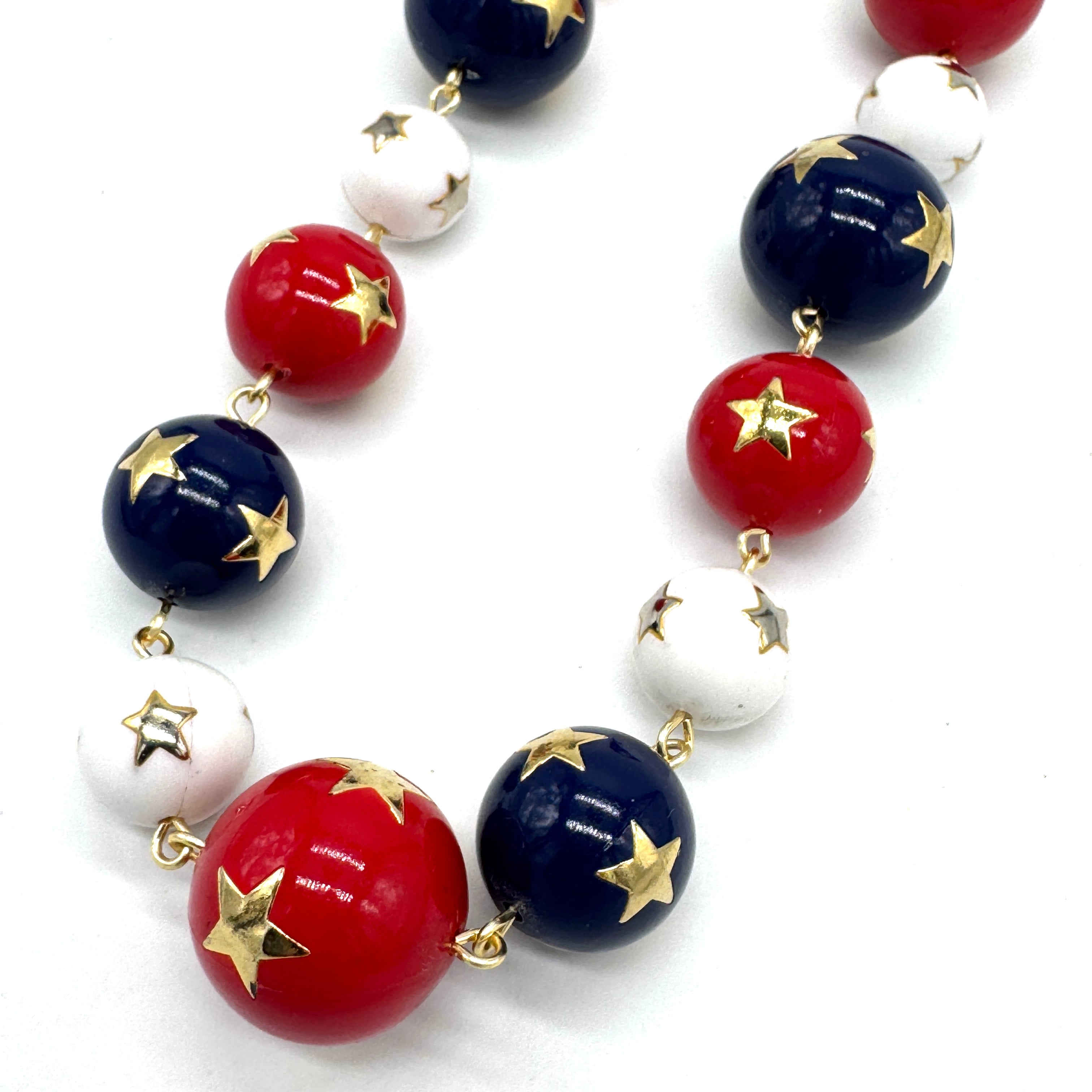 Necklace with red, white, and blue beads with gold stars on a white background
