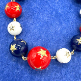 Necklace with red, white, and blue beads with gold stars on a blue background