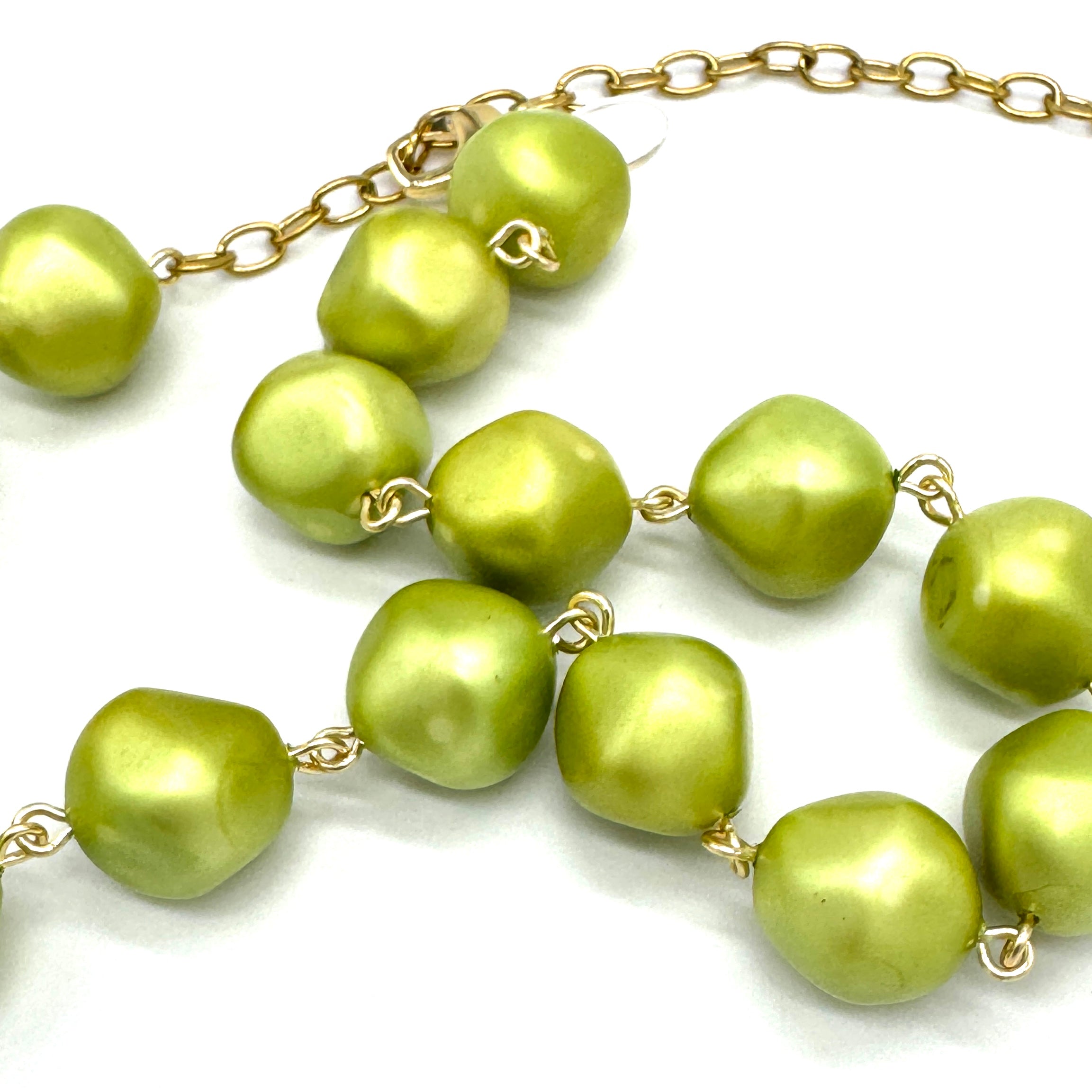 Necklace with green beads and gold chain on a white background