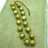 Green necklace on a textured green surface
