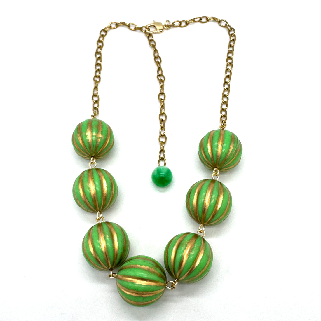 Necklace with green and gold striped beads on a white background