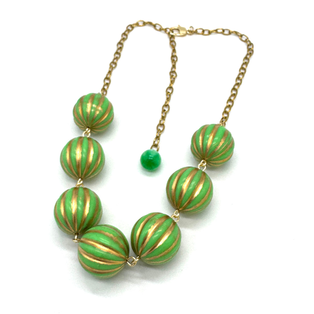 Necklace with green and gold striped beads on a white background