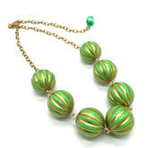 Necklace with green and gold striped beads on a white background