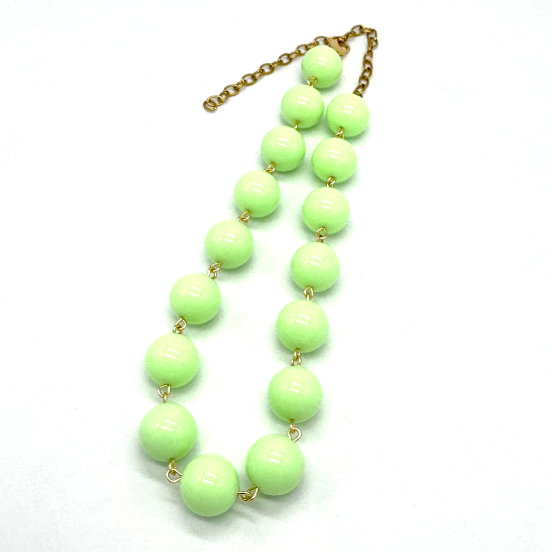Bright green beaded necklace with gold chain on a white background