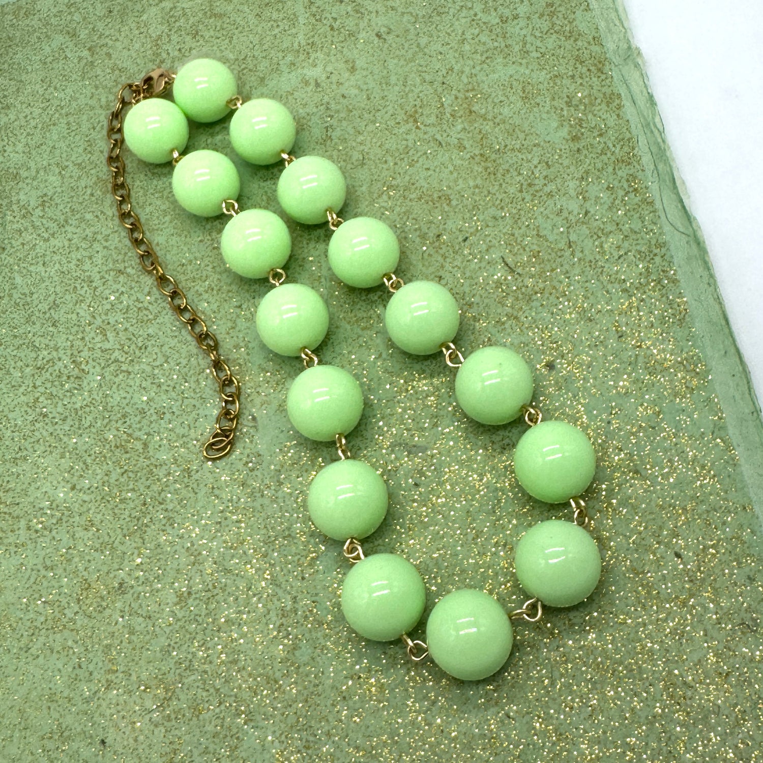Green beaded necklace on a textured green surface