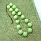 Green beaded necklace on a textured green surface