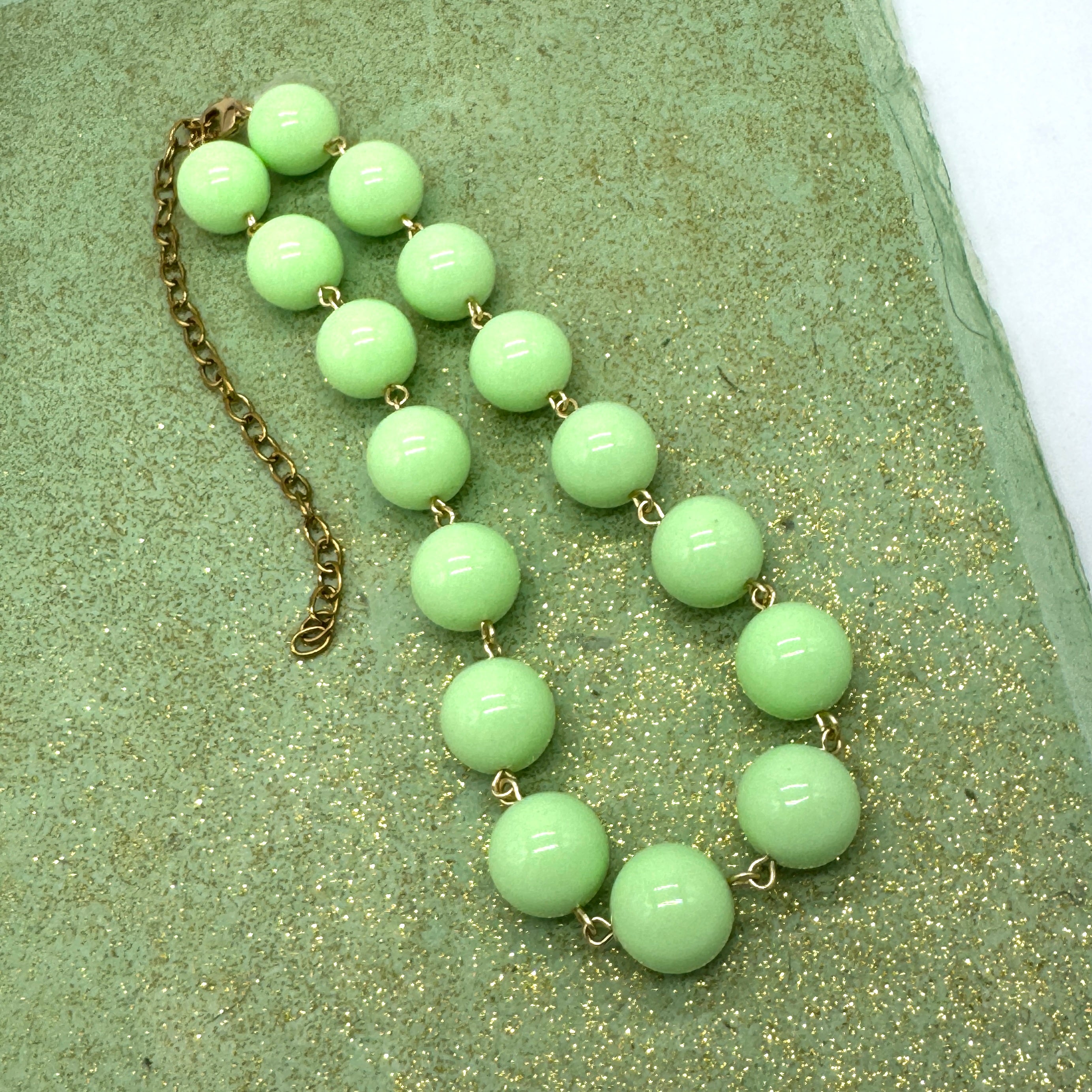 Green beaded necklace on a textured green surface