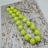 Neon yellow beaded necklace on a textured surface