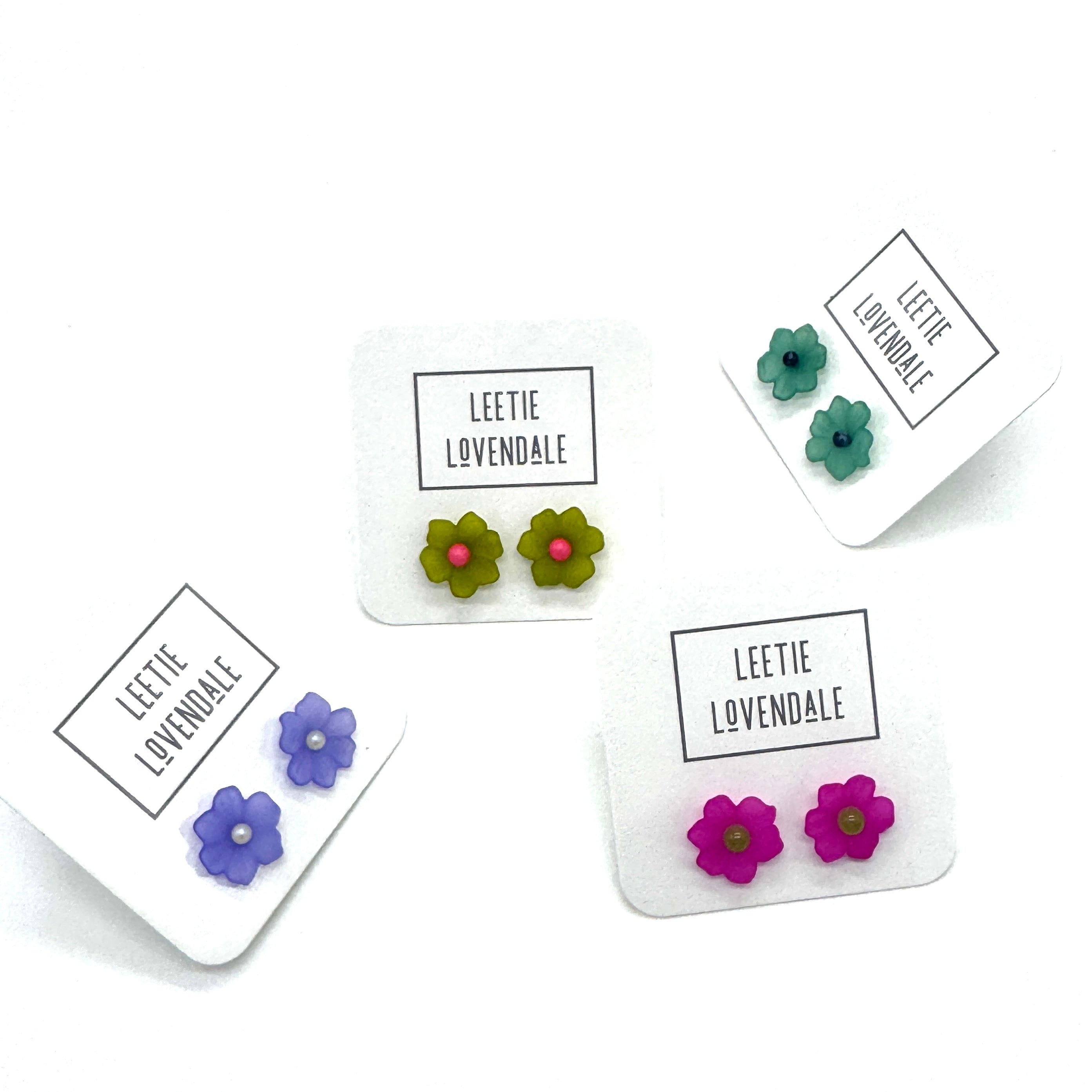four pairs of colorful floral earrings on a white background