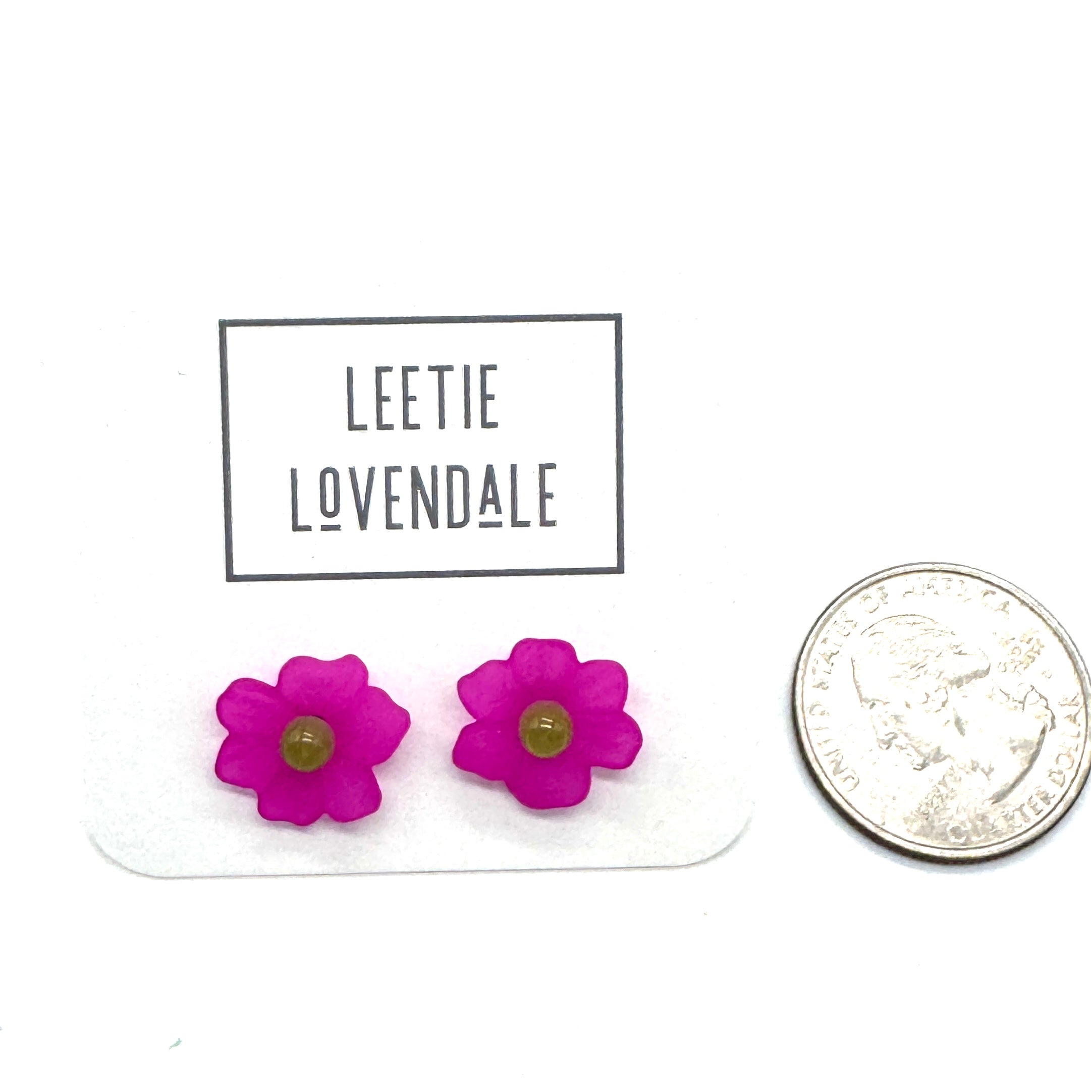 Hot pink flower stud earrings on a white background with a quarter for scale.