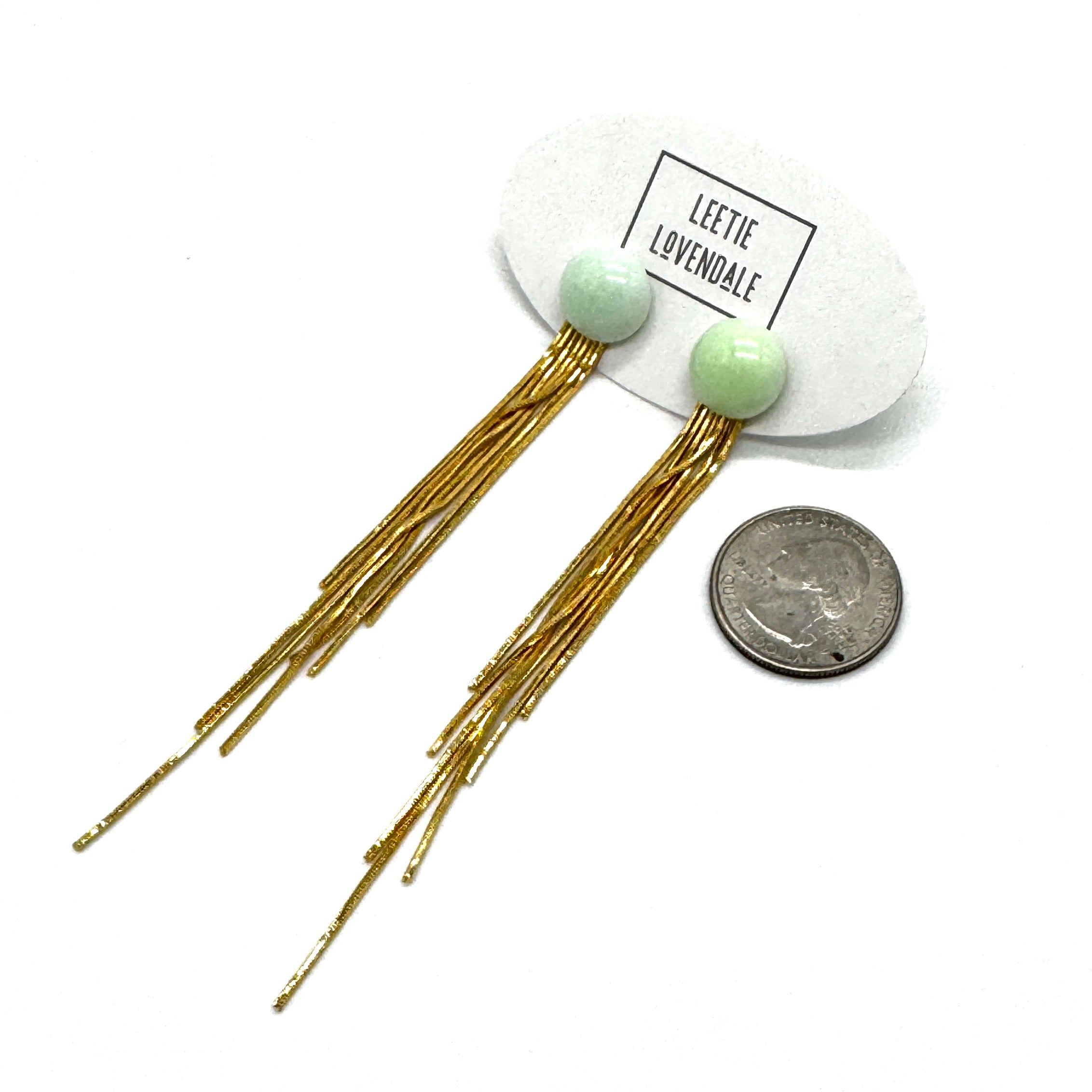 Gold fringe earrings with green beads on a white background, Leetie Lovendale branding visible.
